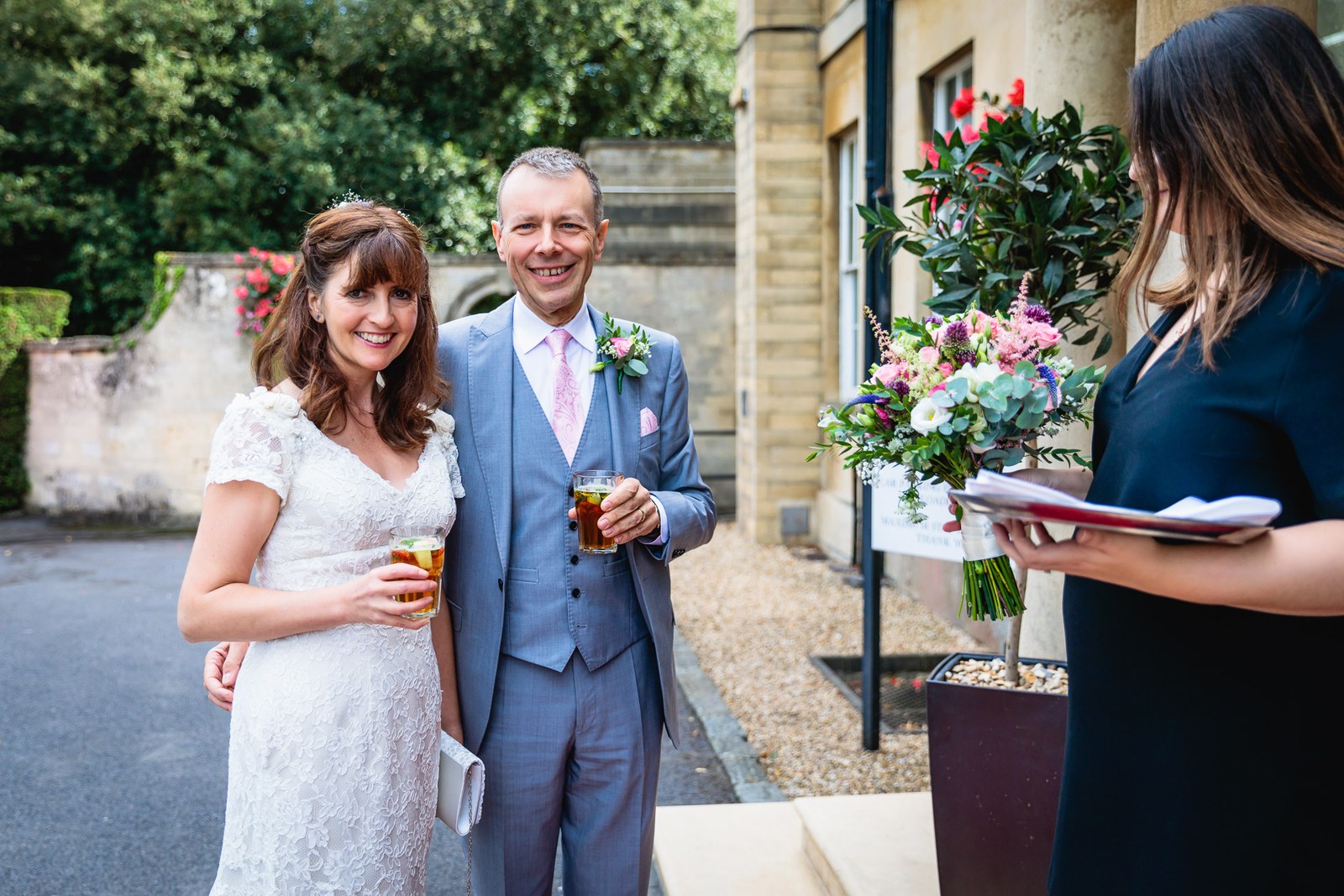 The couple with drinks greeted at the hotel entrance by a member of staff