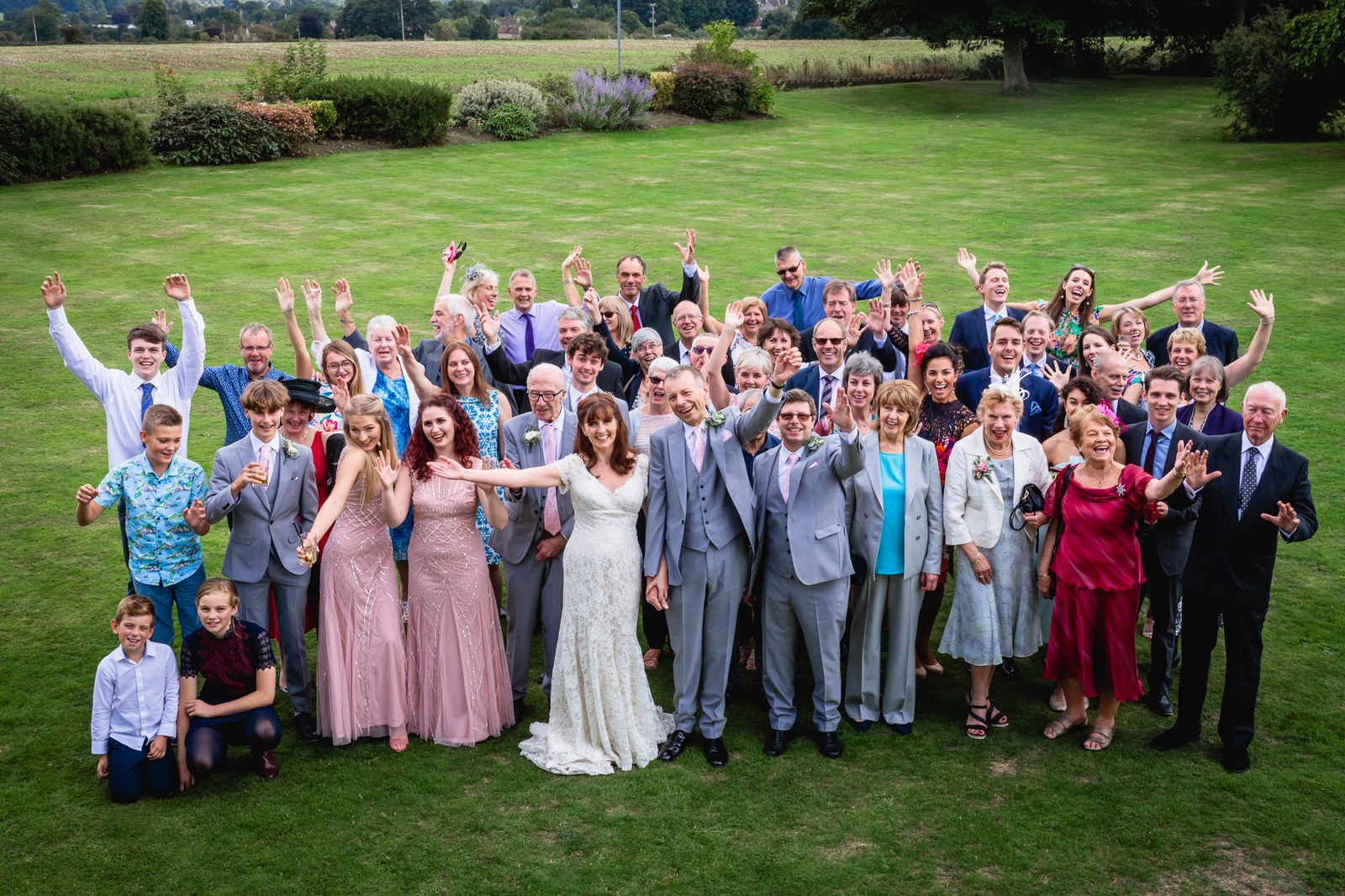 Guests gathered on the hotel lawn raising their arms for a group photograph