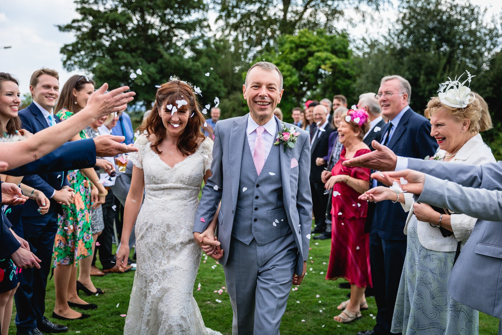 The newlyweds walking hand in hand through a shower of confetti thrown by guests