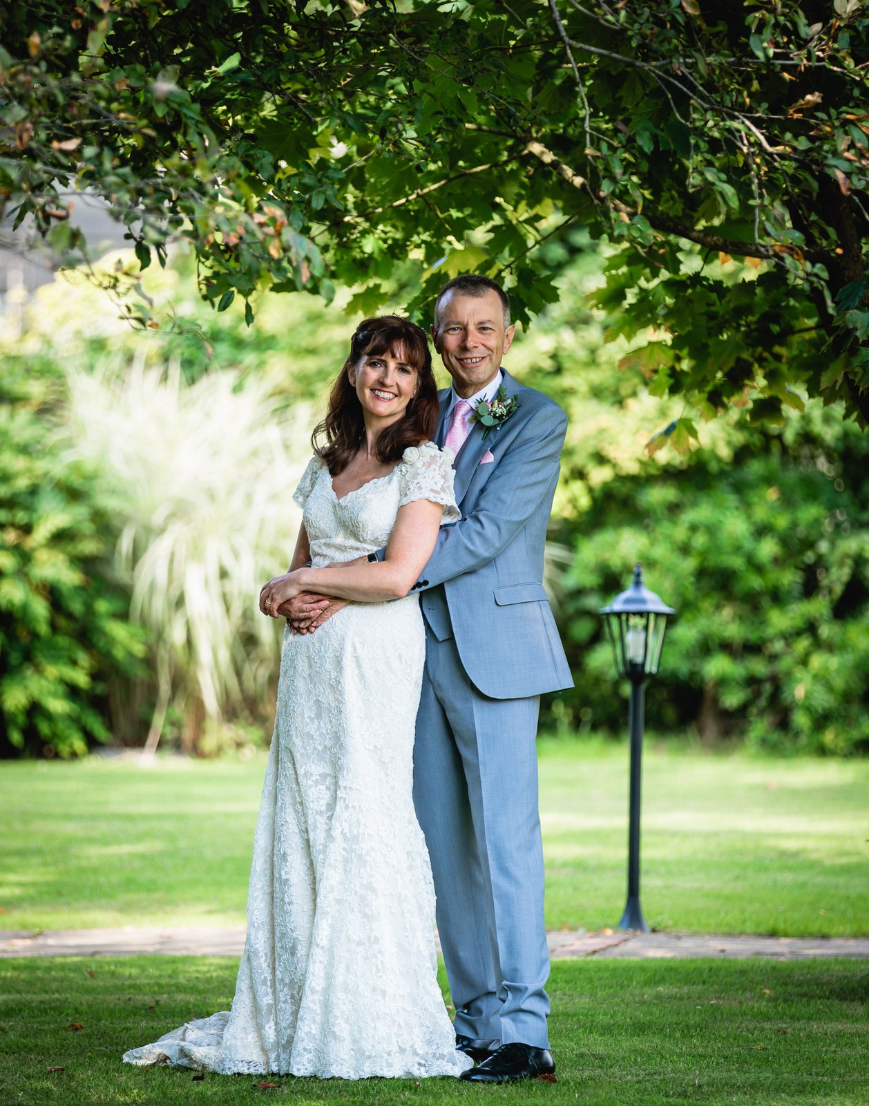 Bride and groom embracing beneath a tree in the hotel grounds