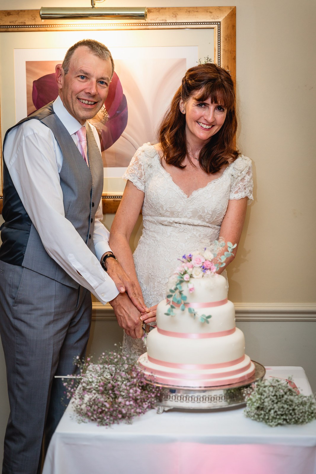 Bride and groom smiling as they cut the cake together