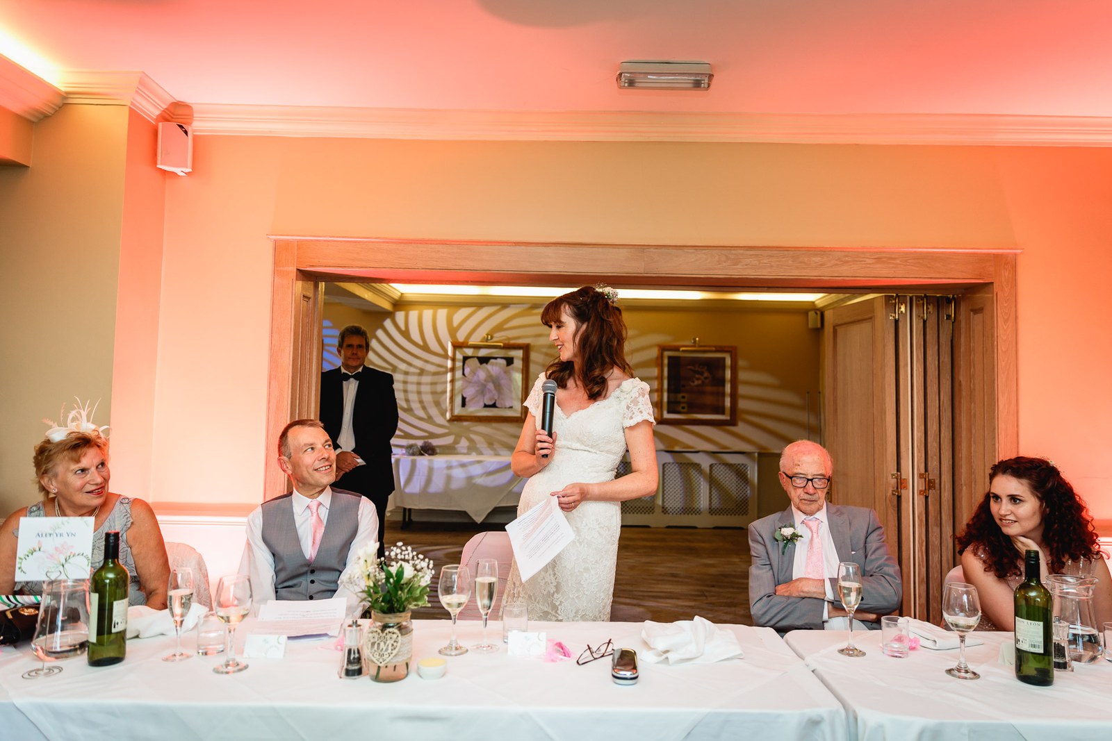 Bride giving a speech at the top table as seated guests listen