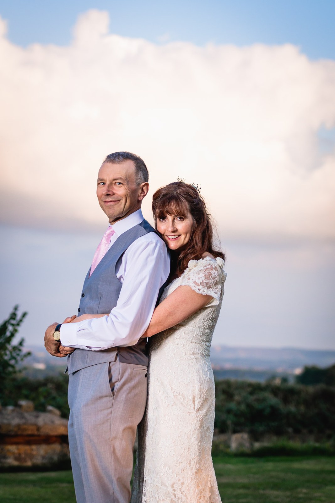 Bride and groom embracing at golden hour with the landscape behind