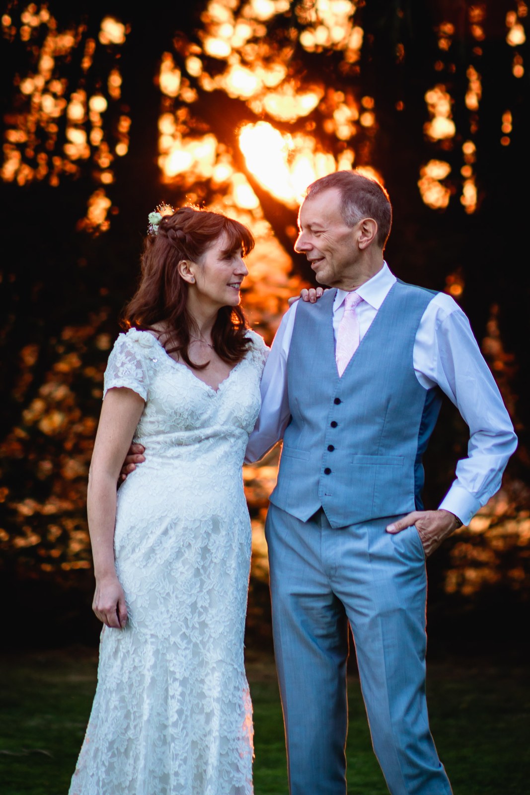 Bride and groom portrait against a fiery sunset glowing through the trees