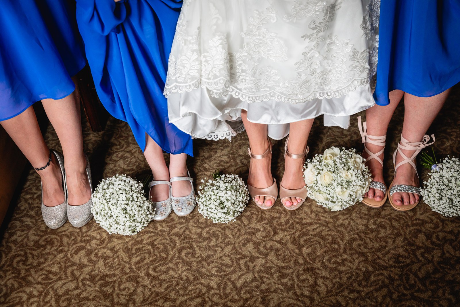 Bridesmaids' feet in blue with the bride's, gypsophila posies lined up on the floor