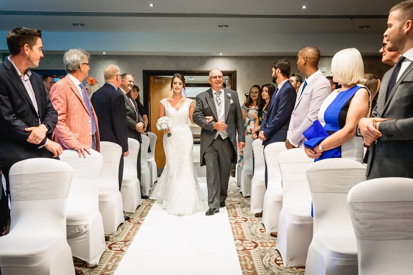 Bride walking down the aisle on her father's arm past standing guests