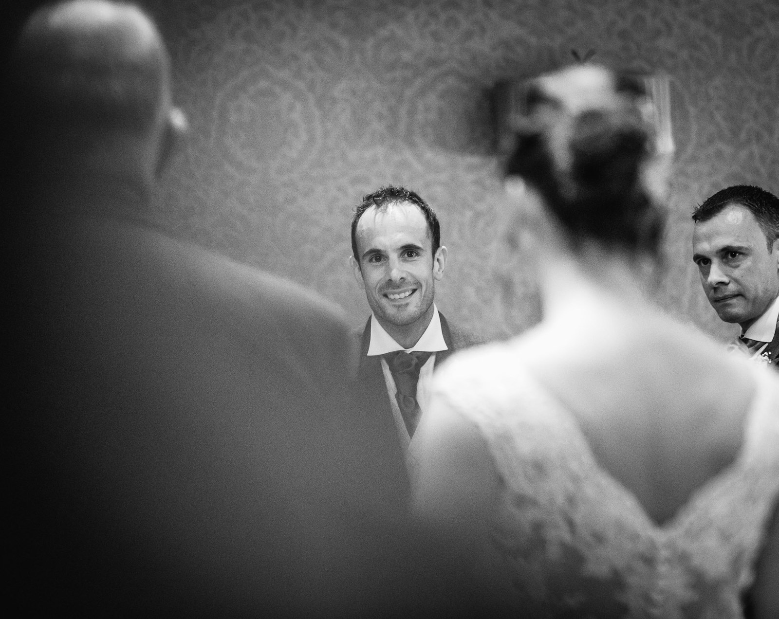 Black and white of the groom watching the bride approach down the aisle
