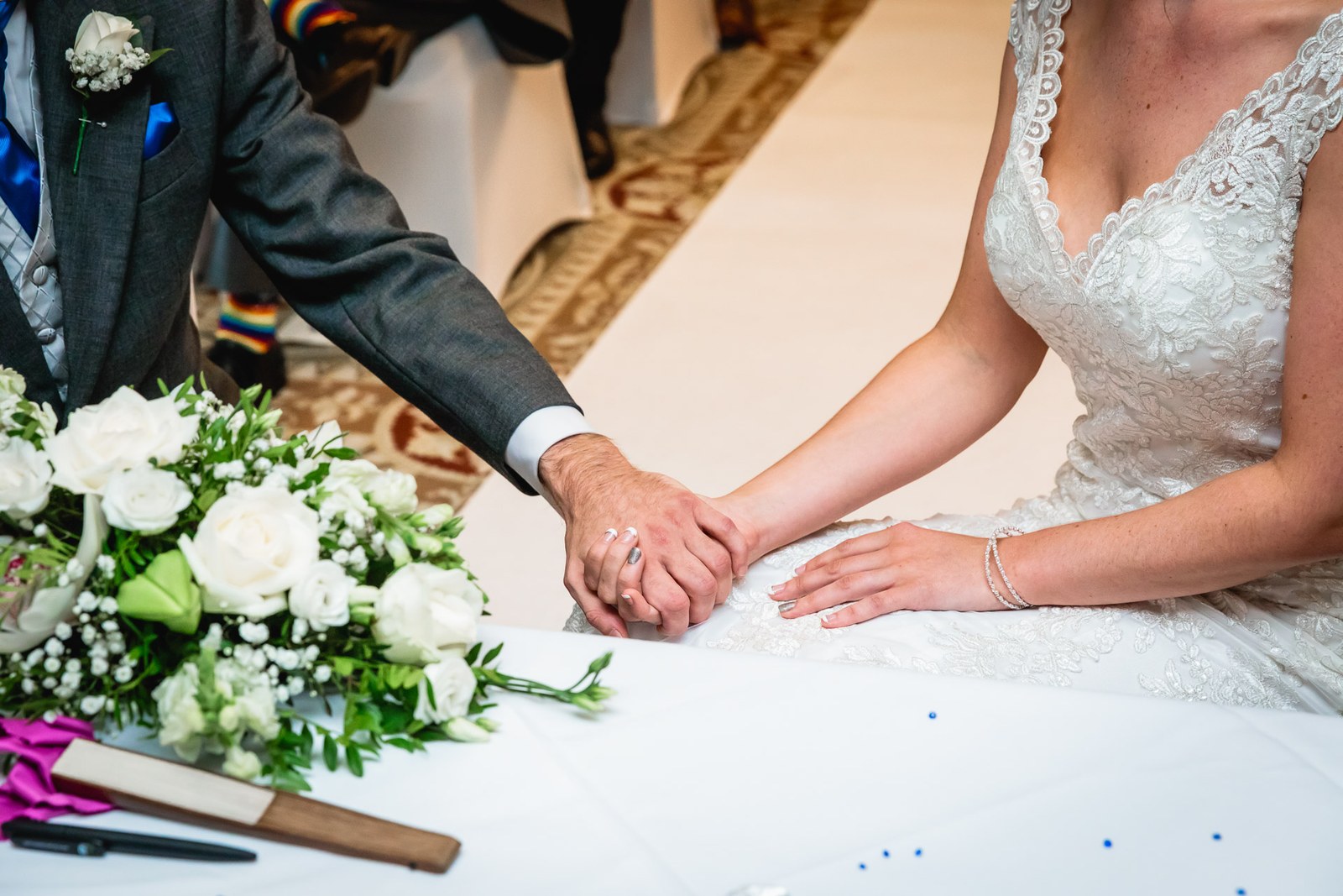 Groom holding the bride's hands during the vows, flowers on the table
