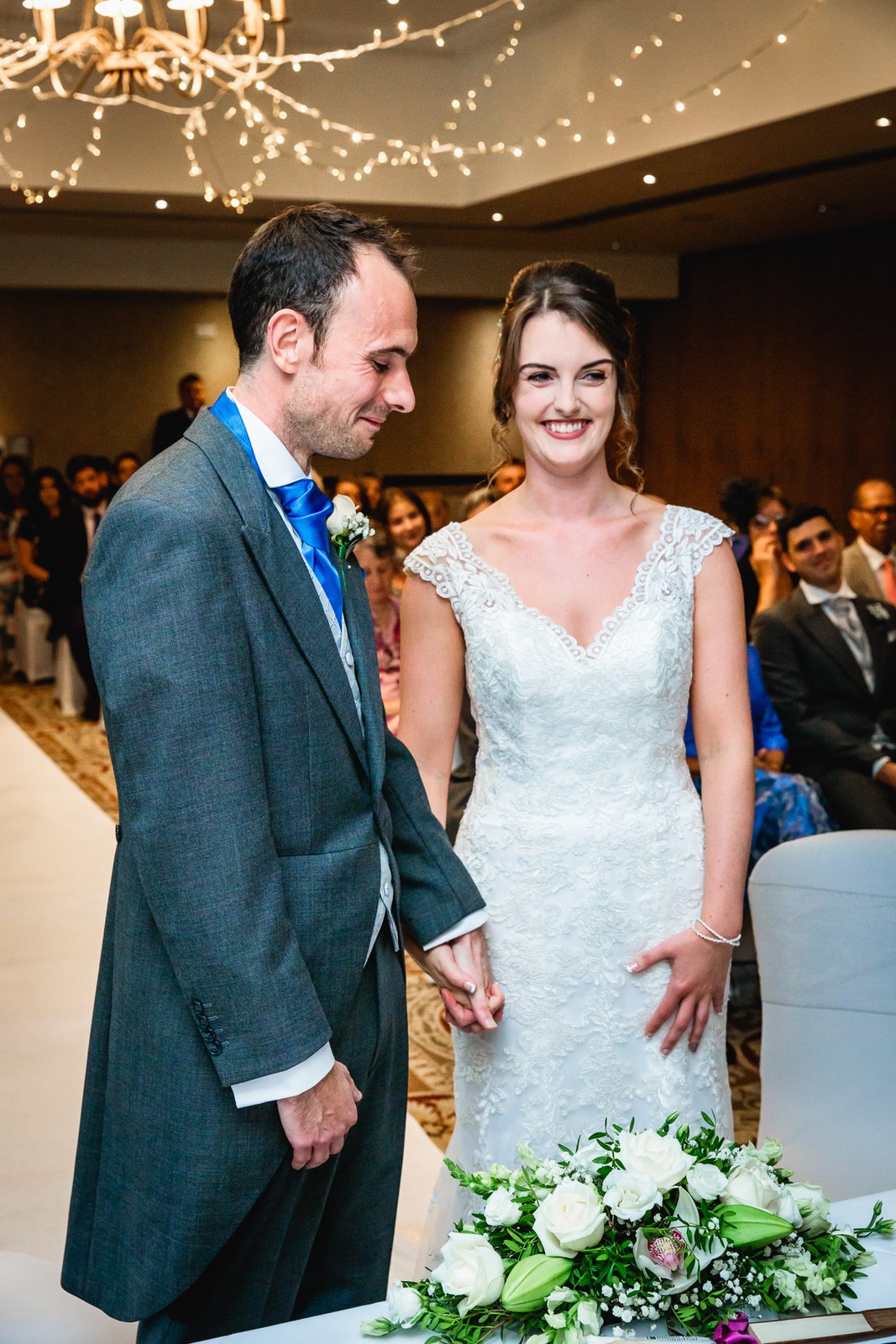 Bride and groom holding hands at the front of the ceremony as guests look on