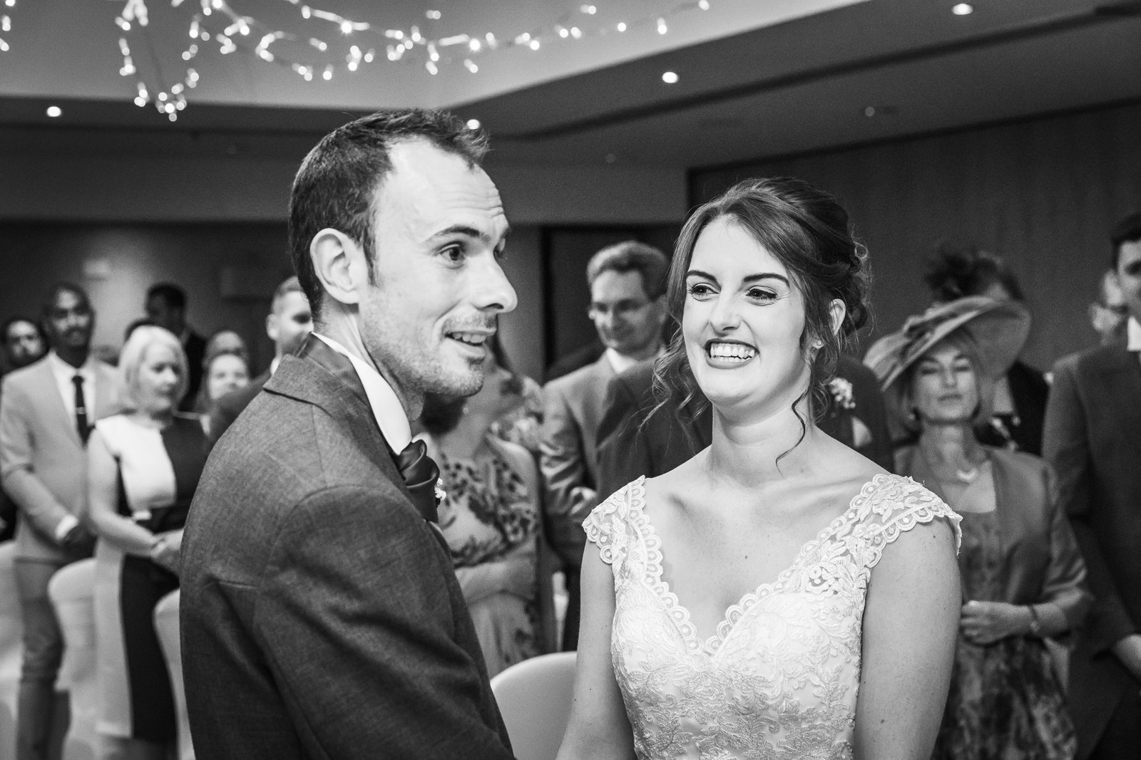 Black and white of the couple smiling at each other during the ceremony