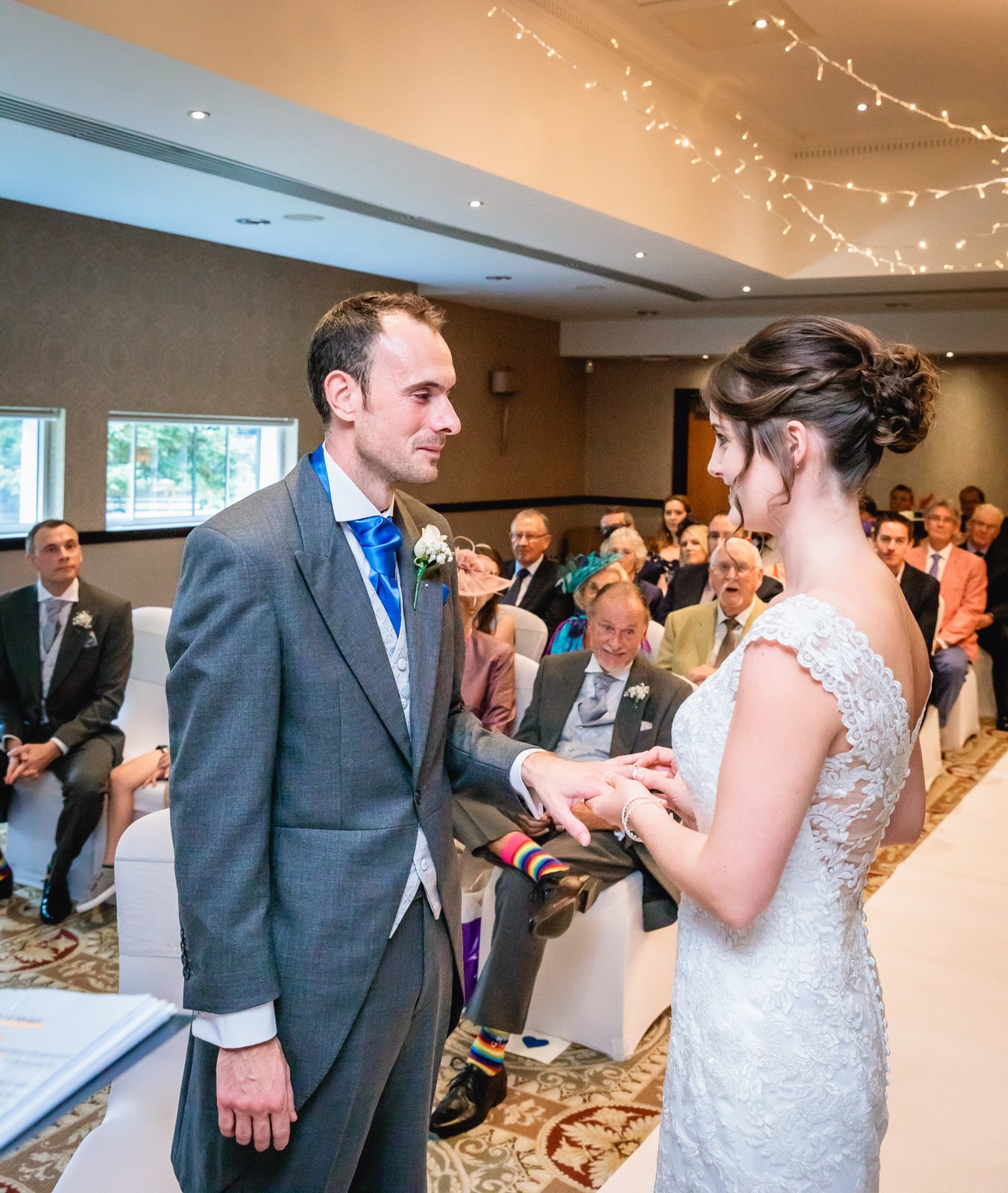 The groom sliding the wedding ring onto the bride's finger