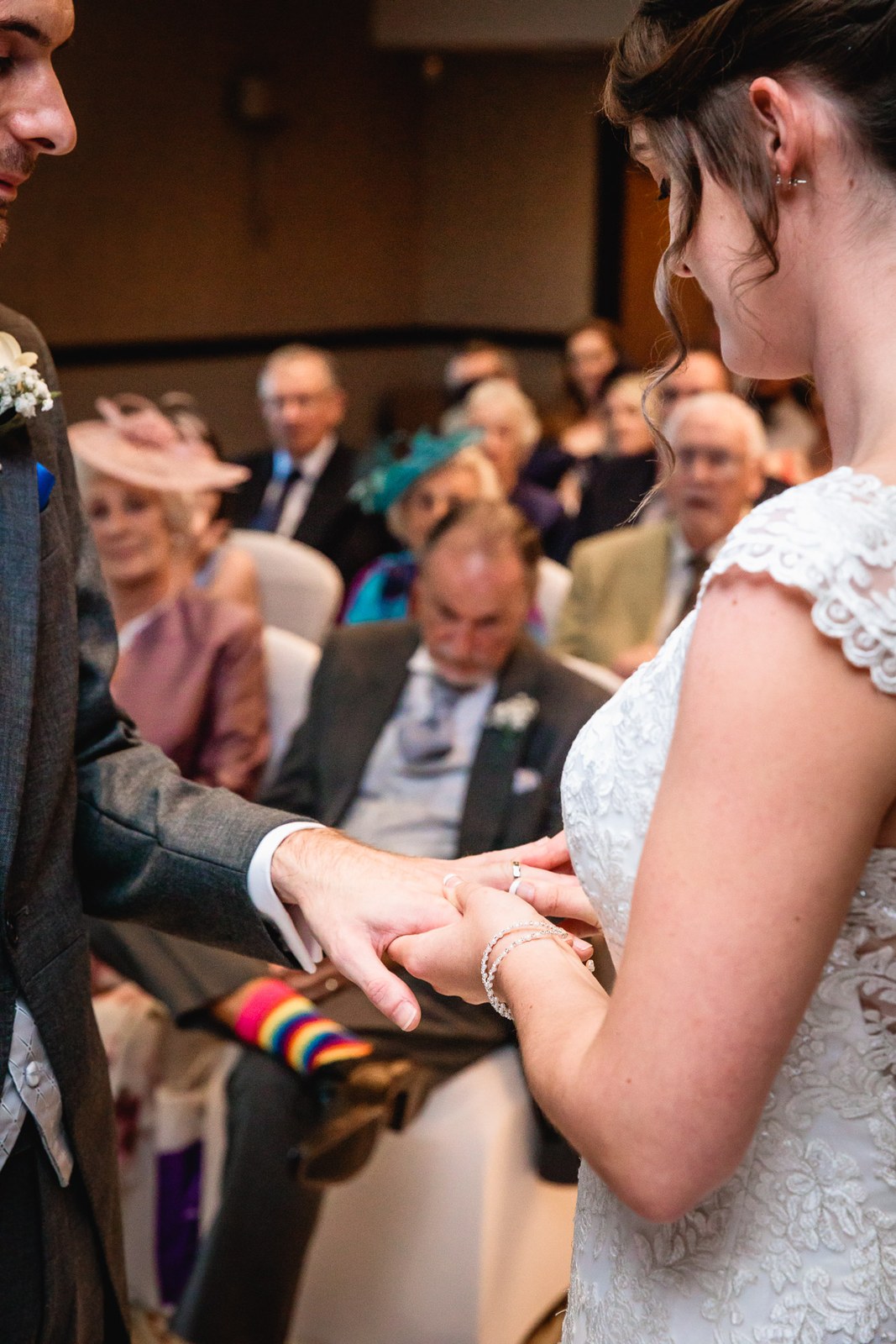 Close-up of the couple exchanging rings with guests seated behind