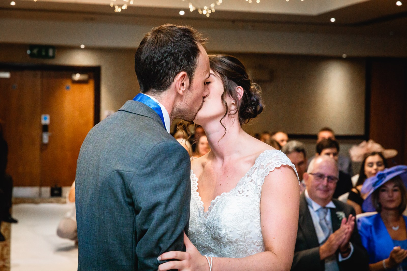 Bride and groom sharing their first kiss as guests applaud