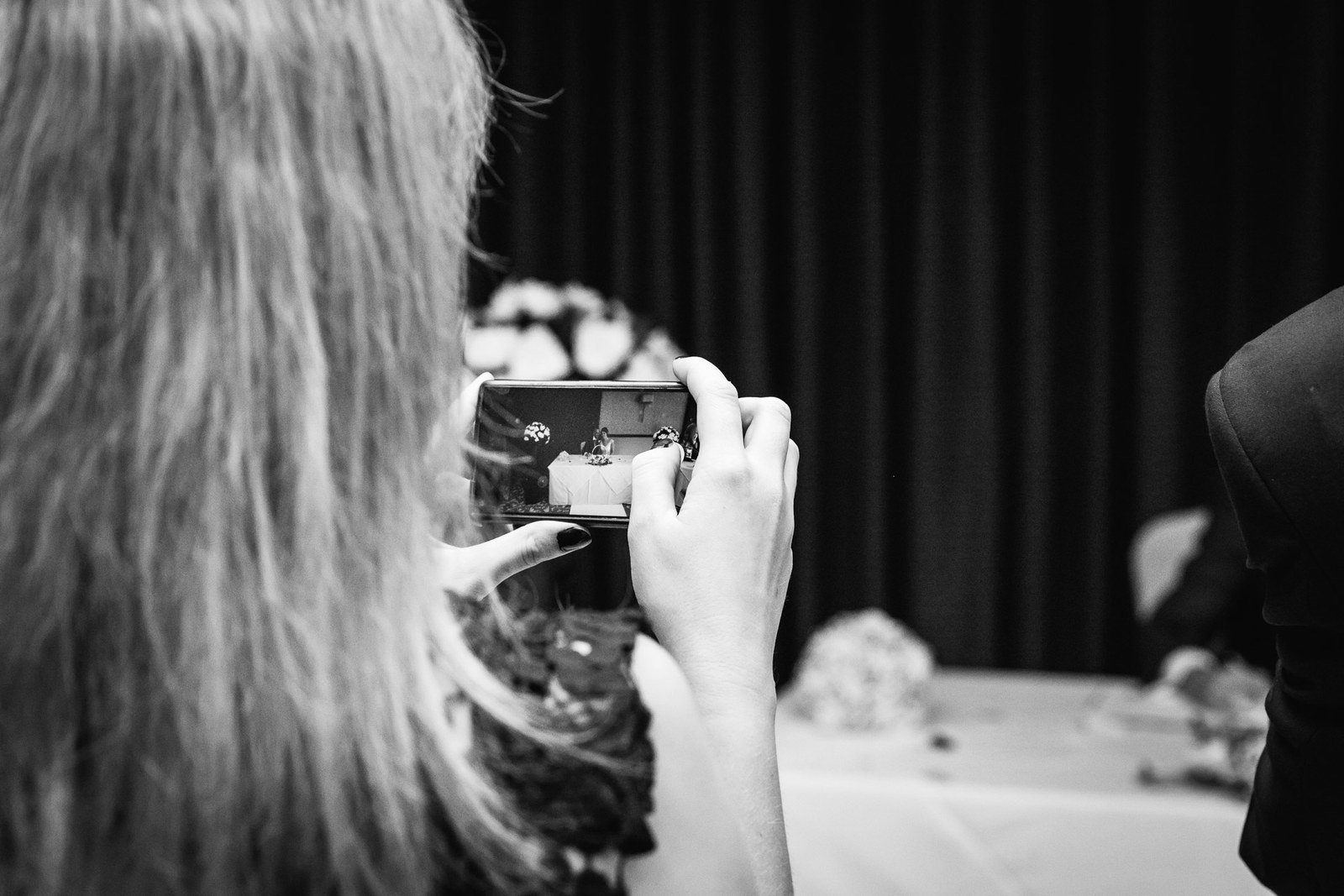 Black and white of a guest photographing the signing on a phone