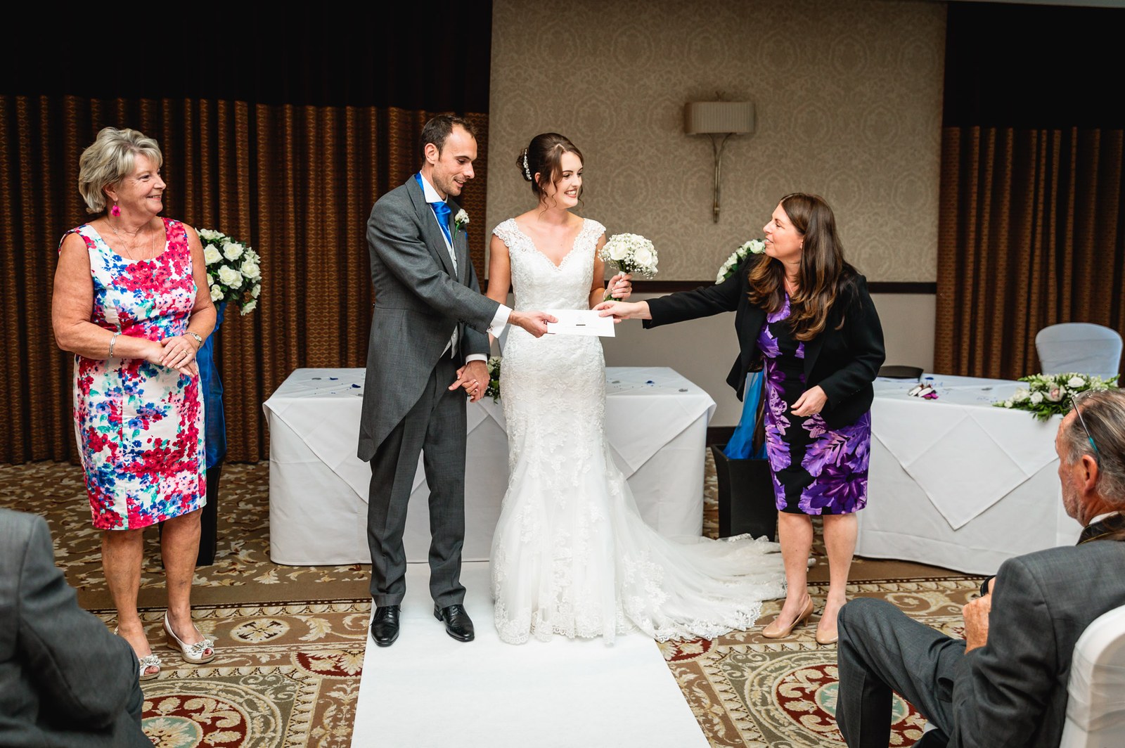 The registrar handing the couple their marriage certificate