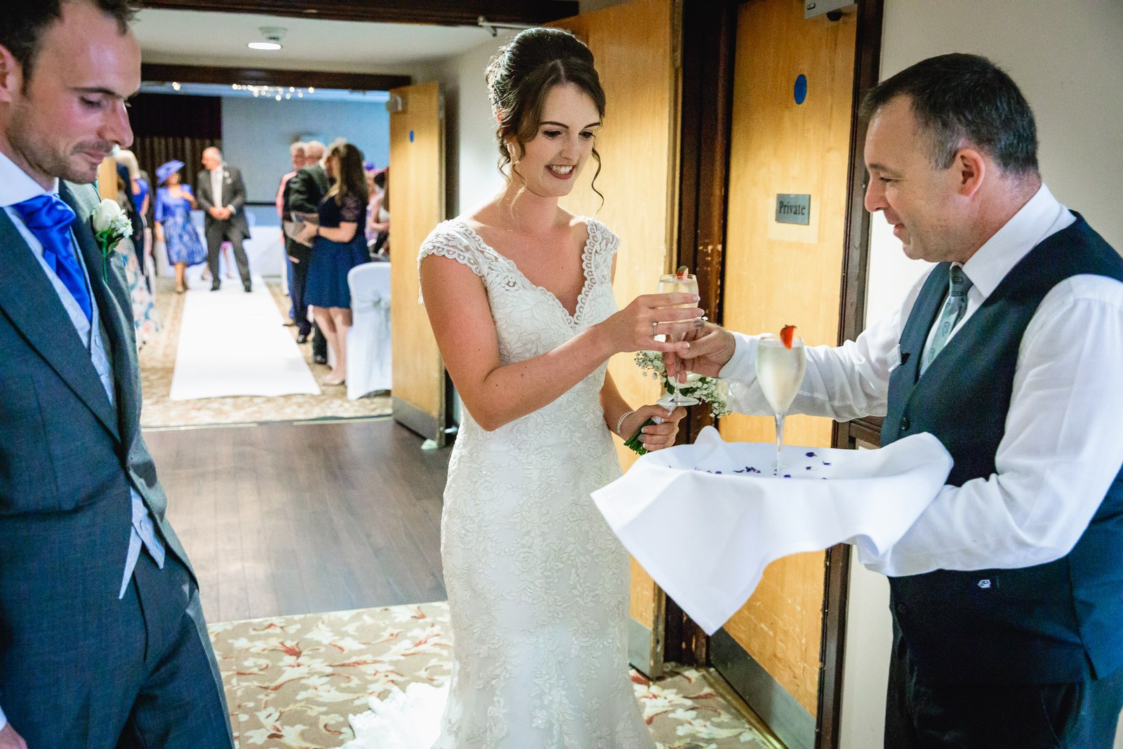 A waiter offering the couple drinks on a tray in the hotel corridor