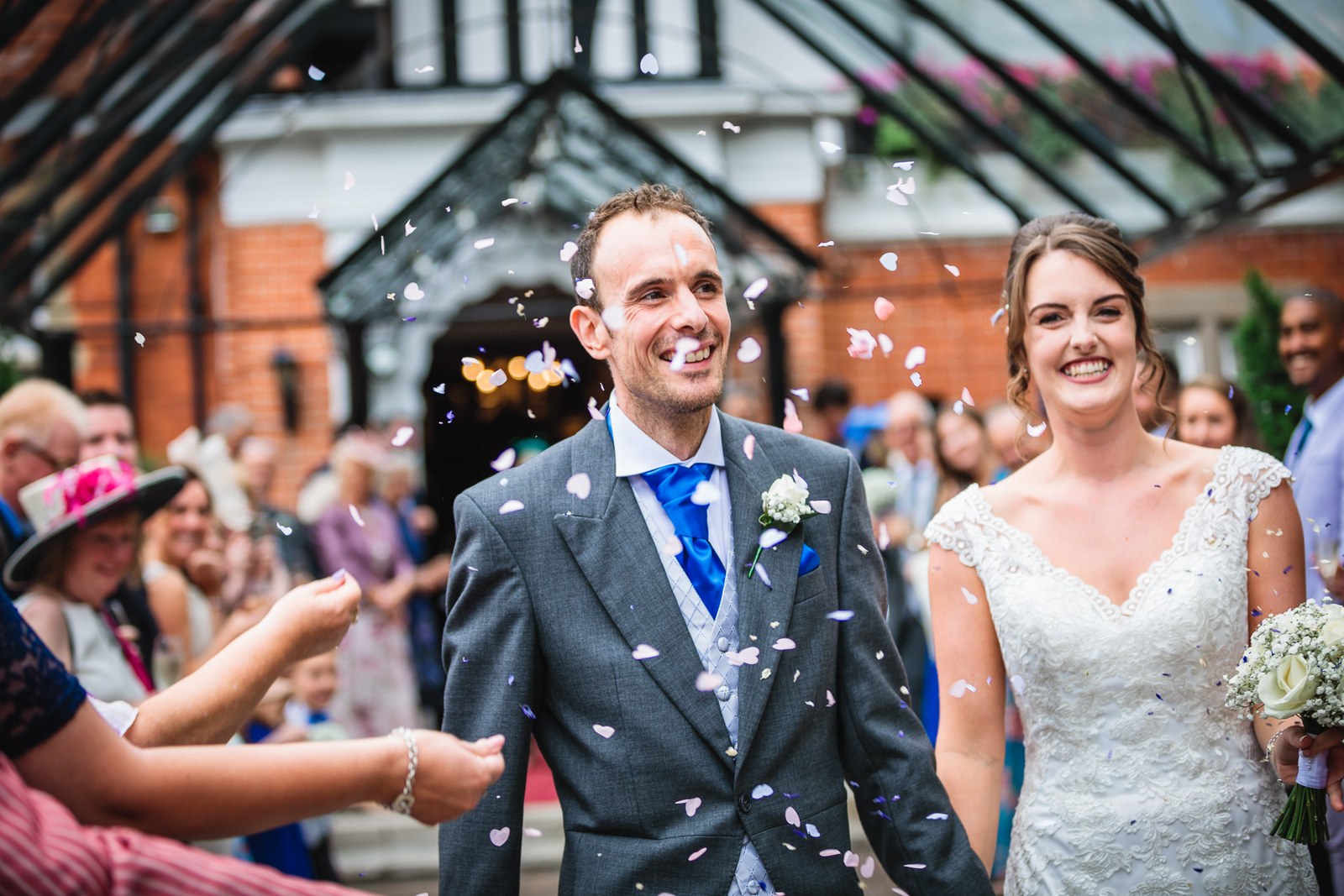 Close-up of the couple as confetti is thrown, brick and timber frontage behind