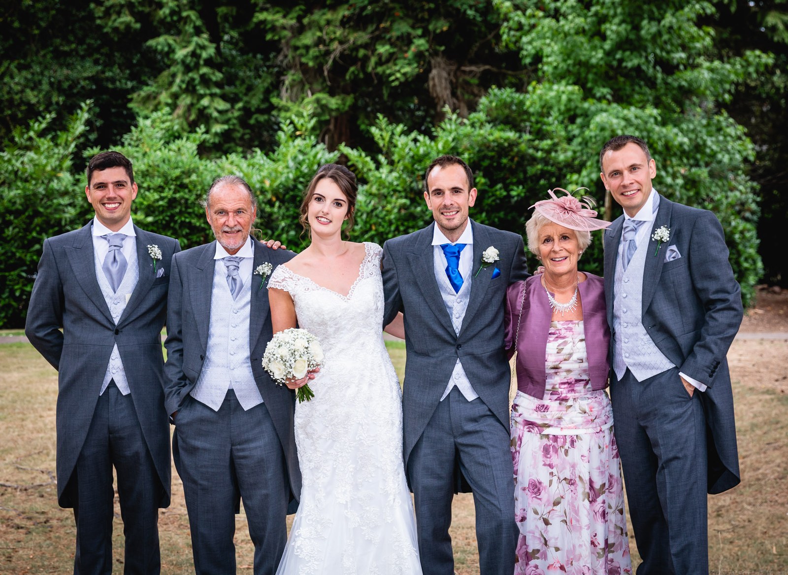 Family group of six in morning suits and hats on the lawn
