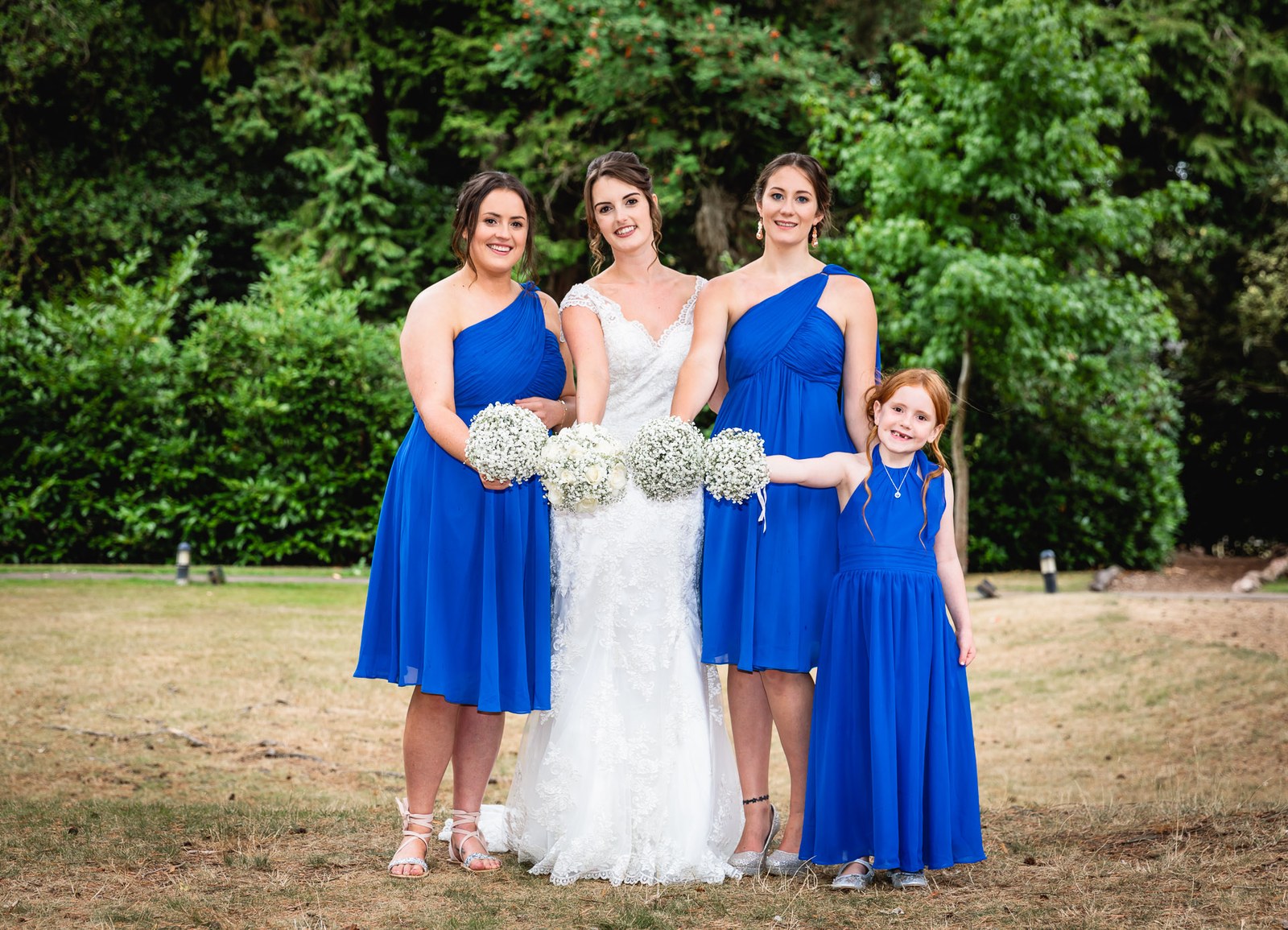 Bride with two bridesmaids in cobalt blue and a flower girl holding gypsophila posies