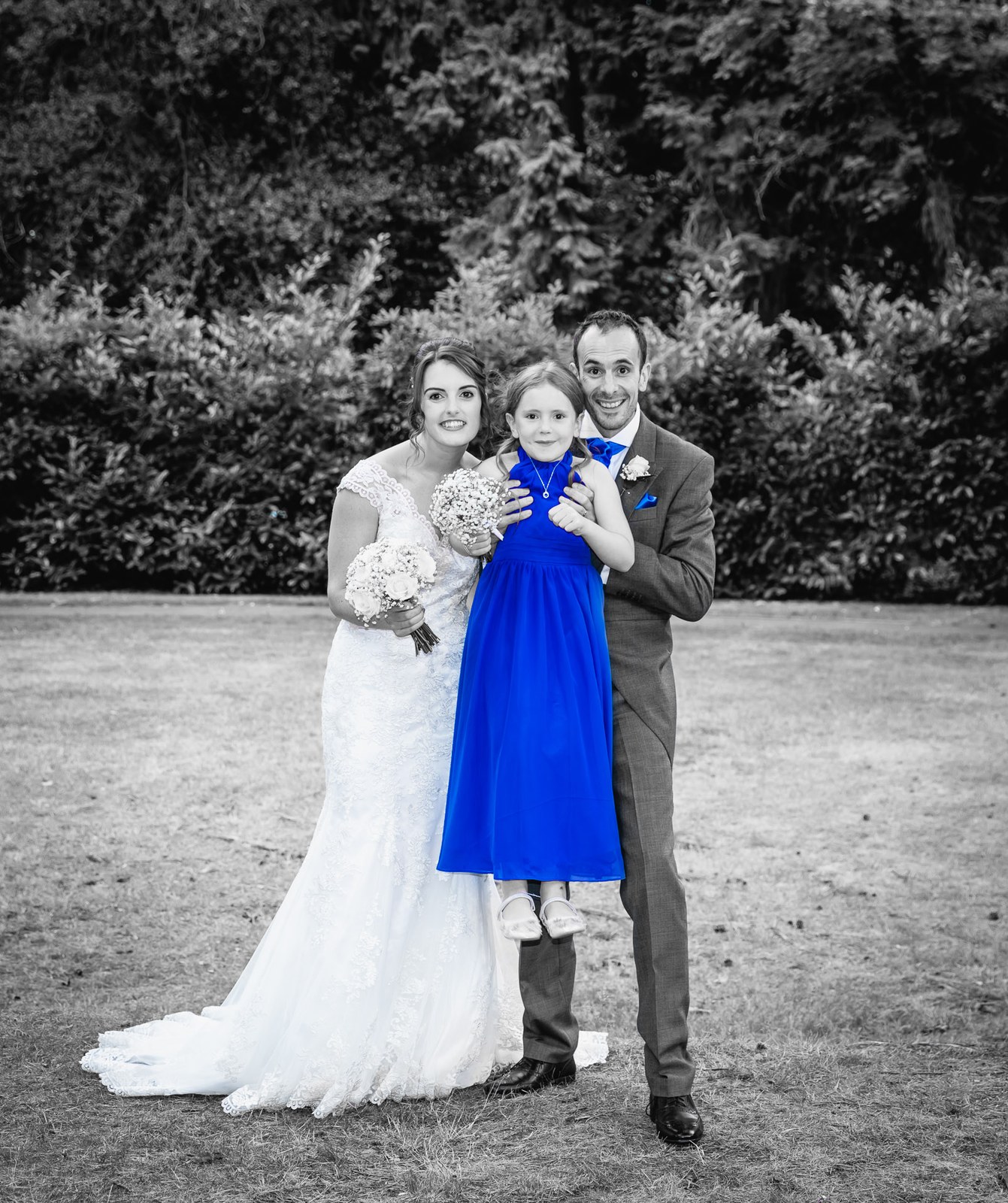 Black and white of the bride and groom with a flower girl in blue