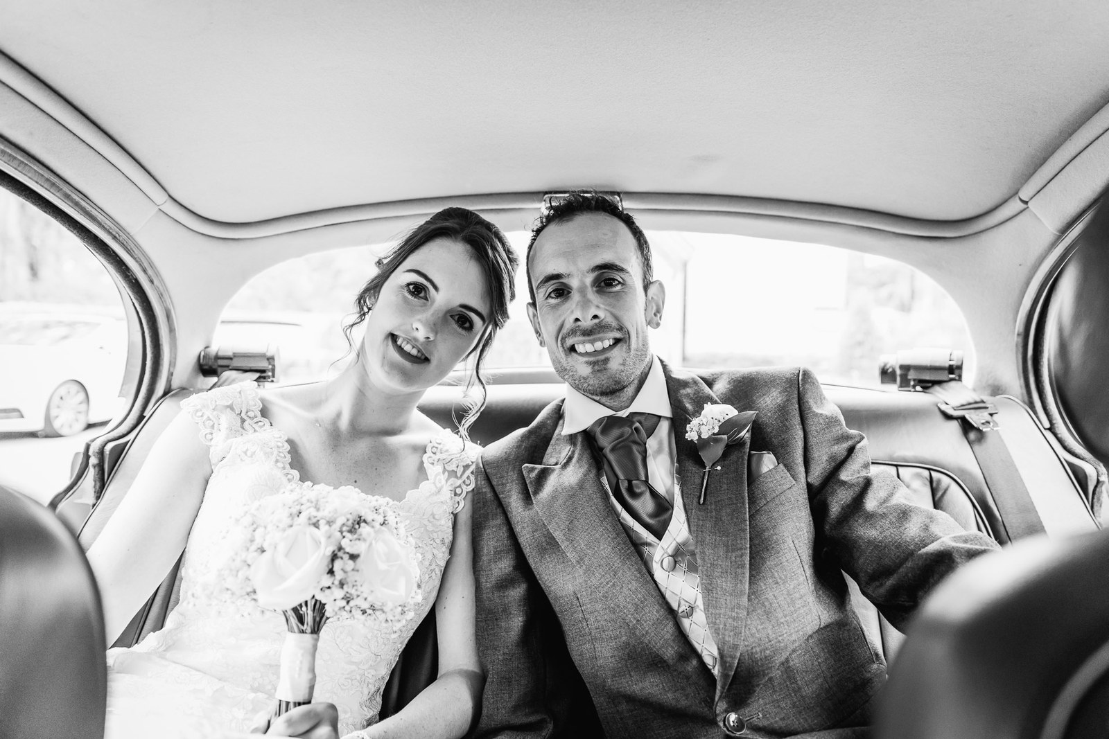 Black and white of the couple sitting close in the back of the wedding car