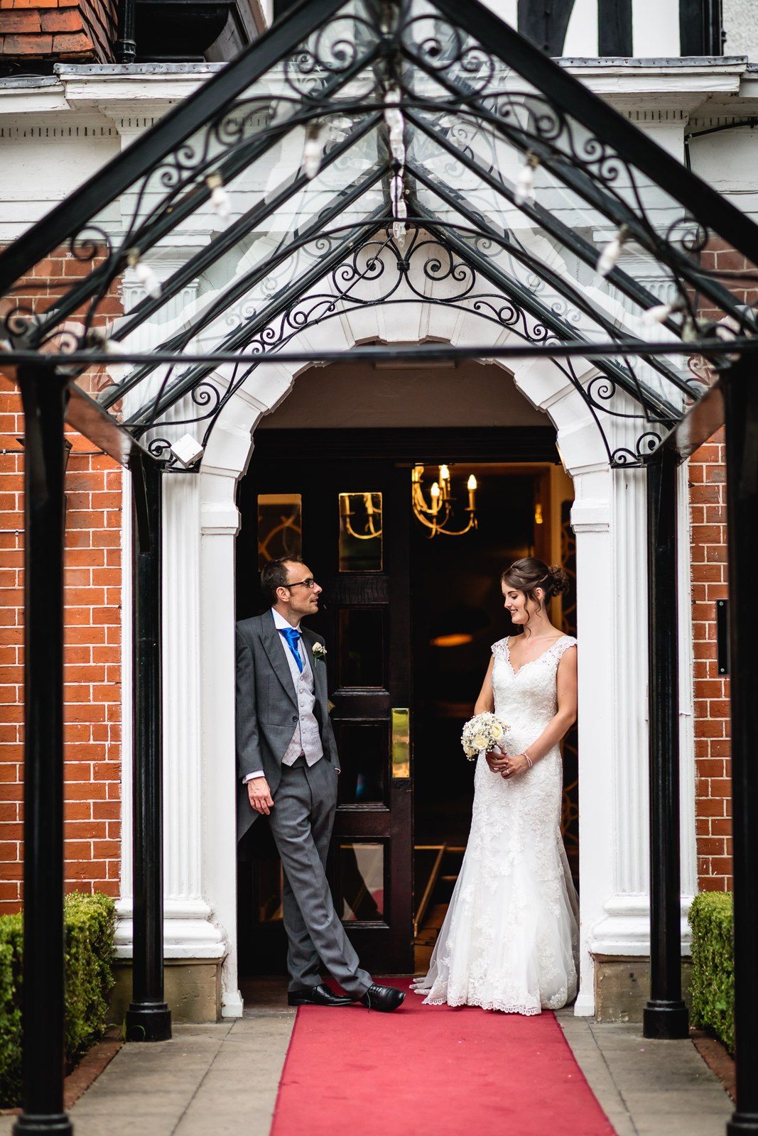 The couple framed in the wrought-iron and glass entrance porch of Macdonald Berystede Hotel