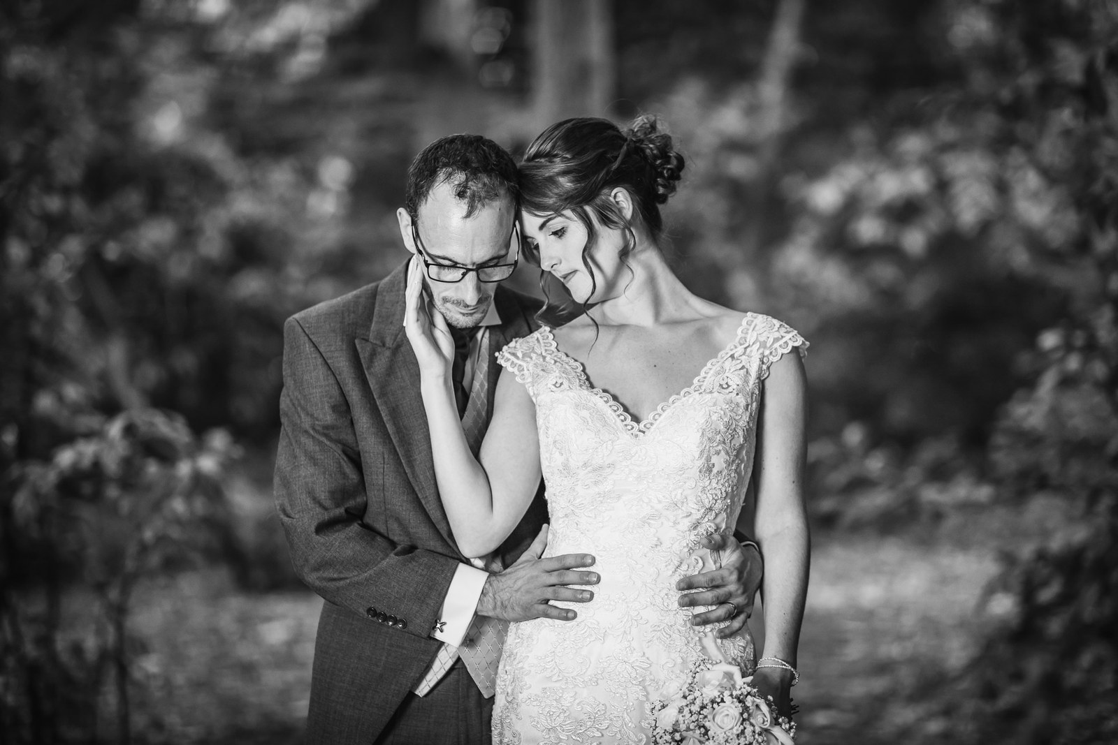 Black and white portrait of the couple embracing in the woodland grounds