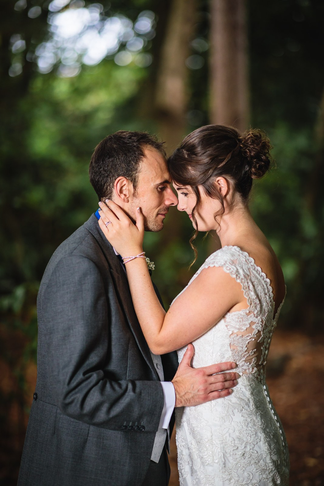 Bride and groom resting their foreheads together in the wooded grounds