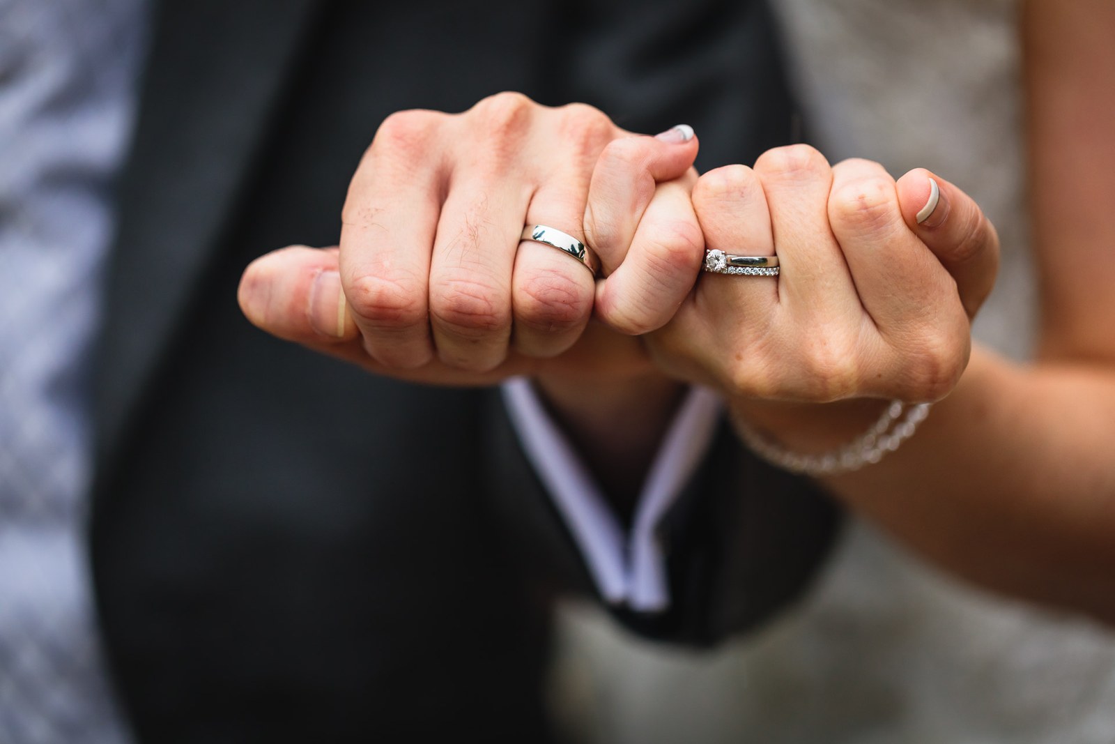 Close-up of the couple's fists together showing their wedding rings