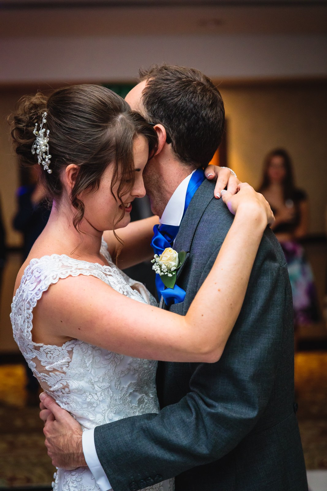 Bride and groom's first dance with foreheads together, guests watching
