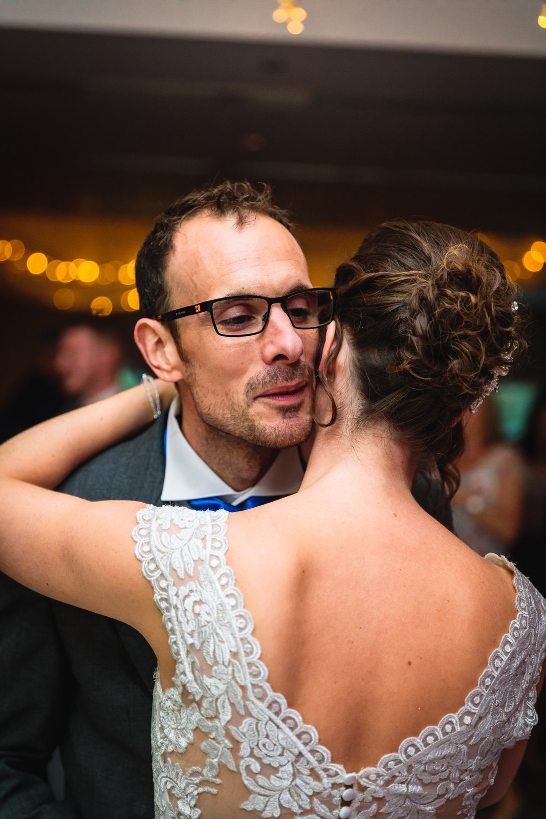 Bride and groom dancing cheek to cheek under warm lights