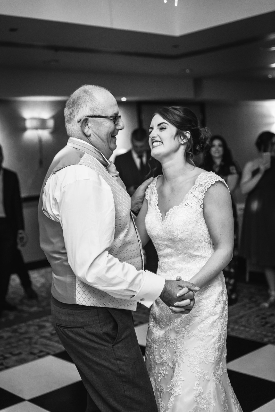 Black and white of the bride dancing with an older man in a silver waistcoat