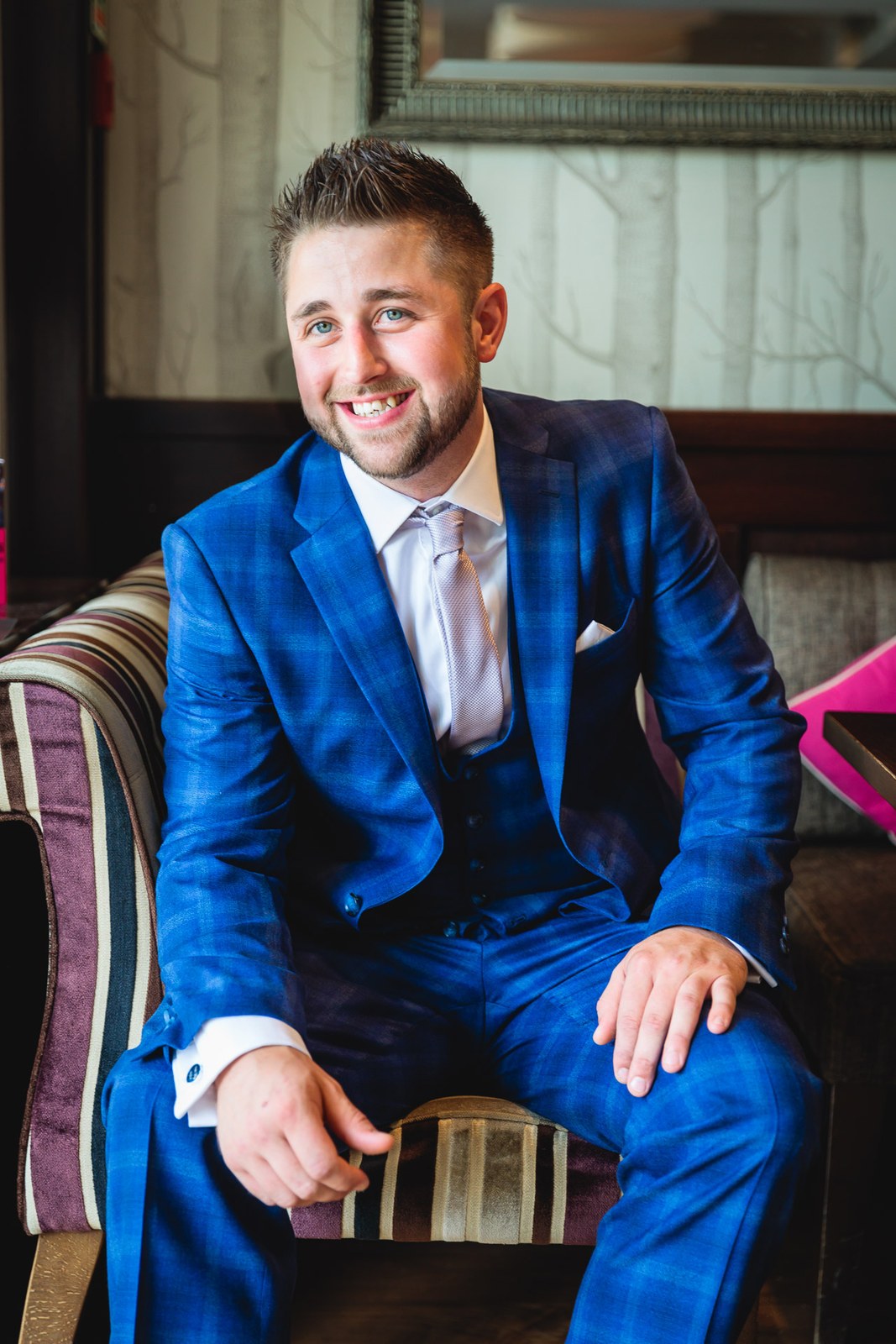 Groom in his blue suit seated and smiling before the ceremony