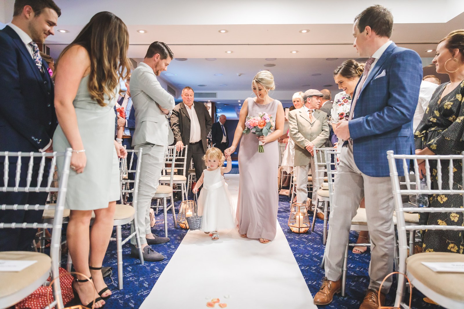 Bridesmaid and flower girl coming down the aisle as guests stand