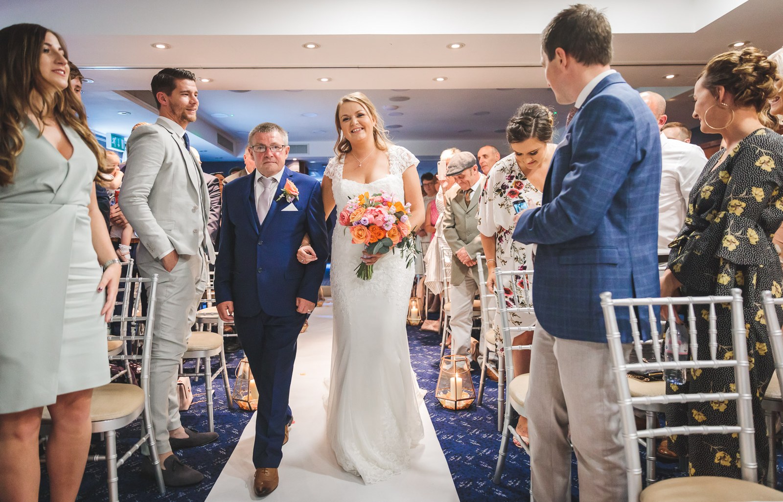 Bride walking down the aisle on her father's arm, guests either side