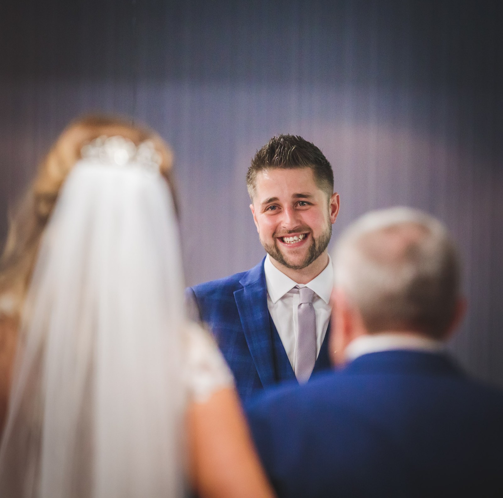 Groom beaming as he meets the bride at the front of the ceremony