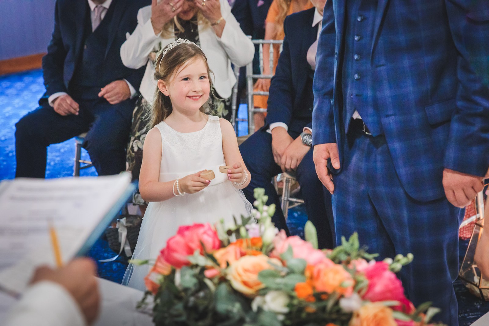 A flower girl smiling as she holds the rings during the ceremony
