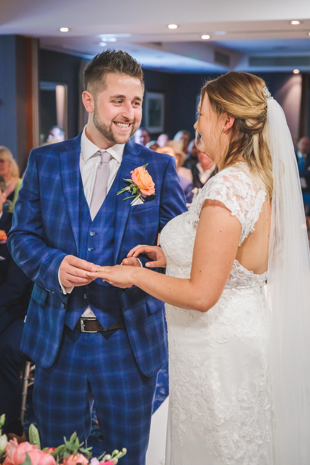 The groom sliding the wedding ring onto the bride's finger