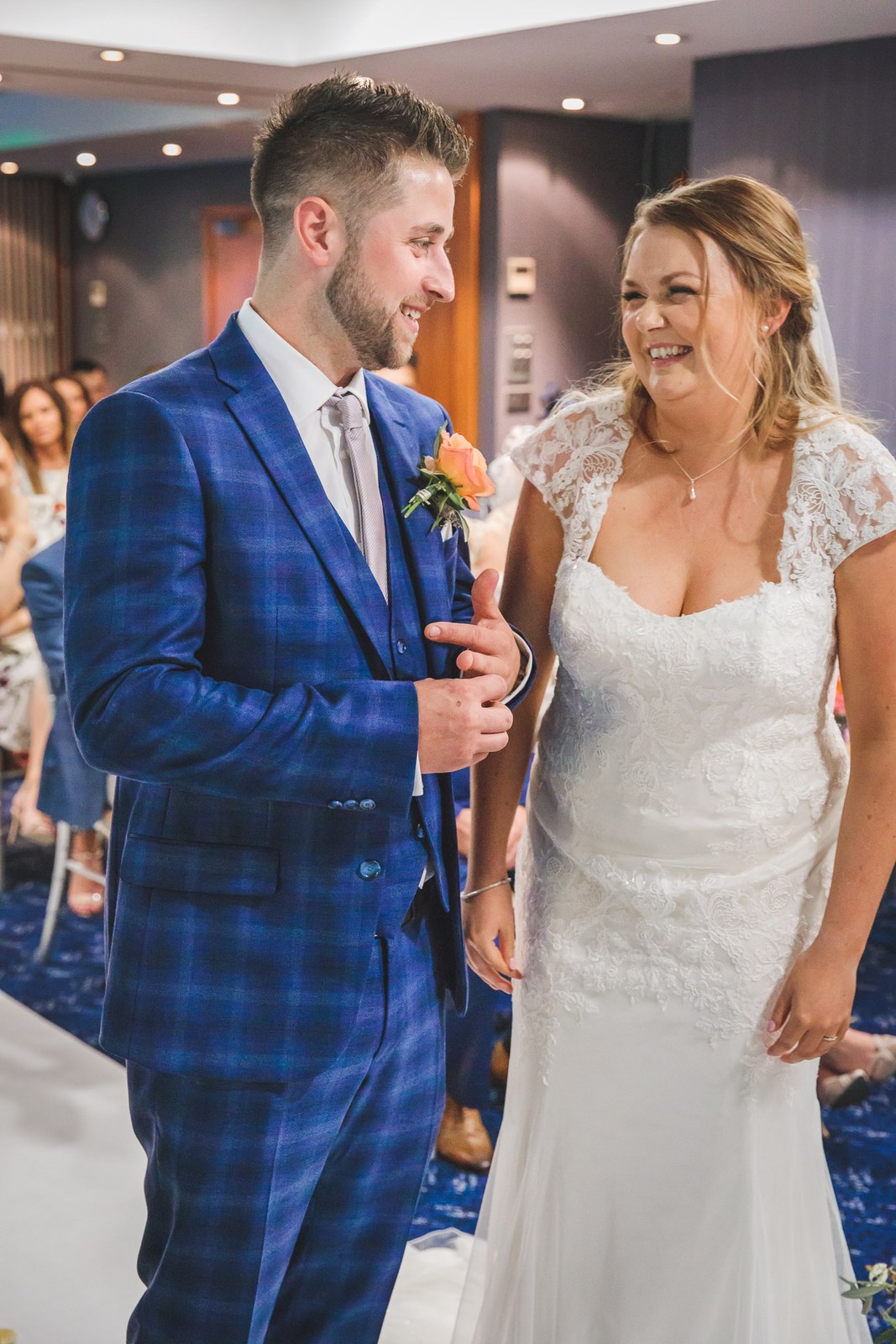 Bride and groom smiling at one another as seated guests look on
