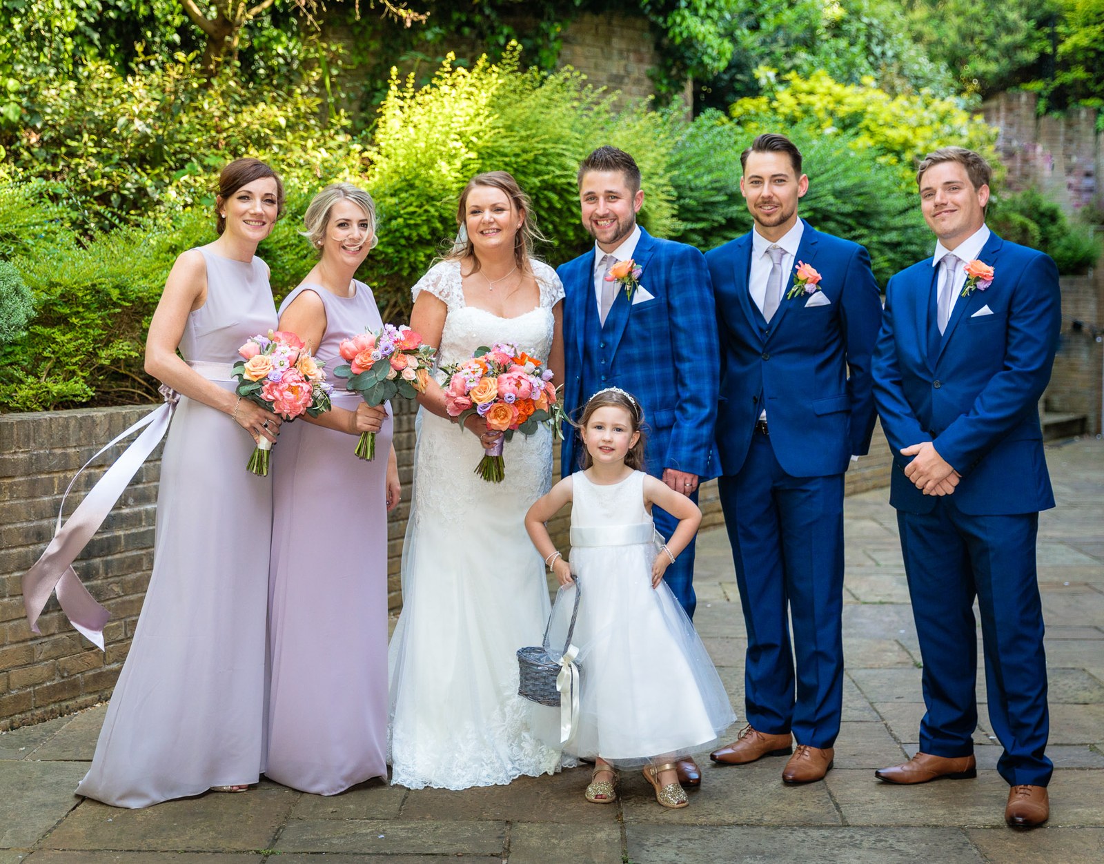 The full bridal party in the garden, bridesmaids in mauve and groomsmen in blue