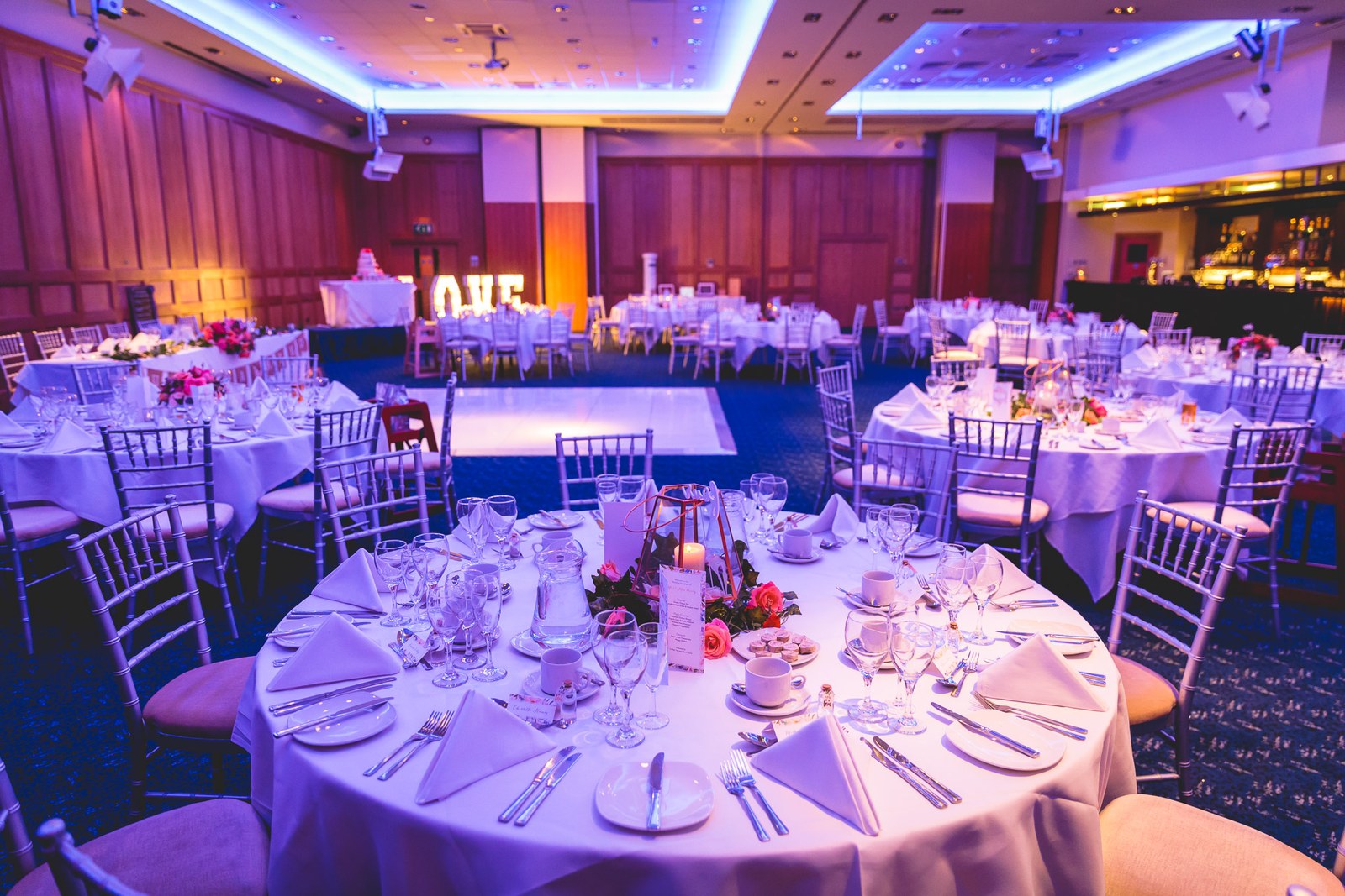 The Mandolay Hotel reception room set with round tables under purple uplighting