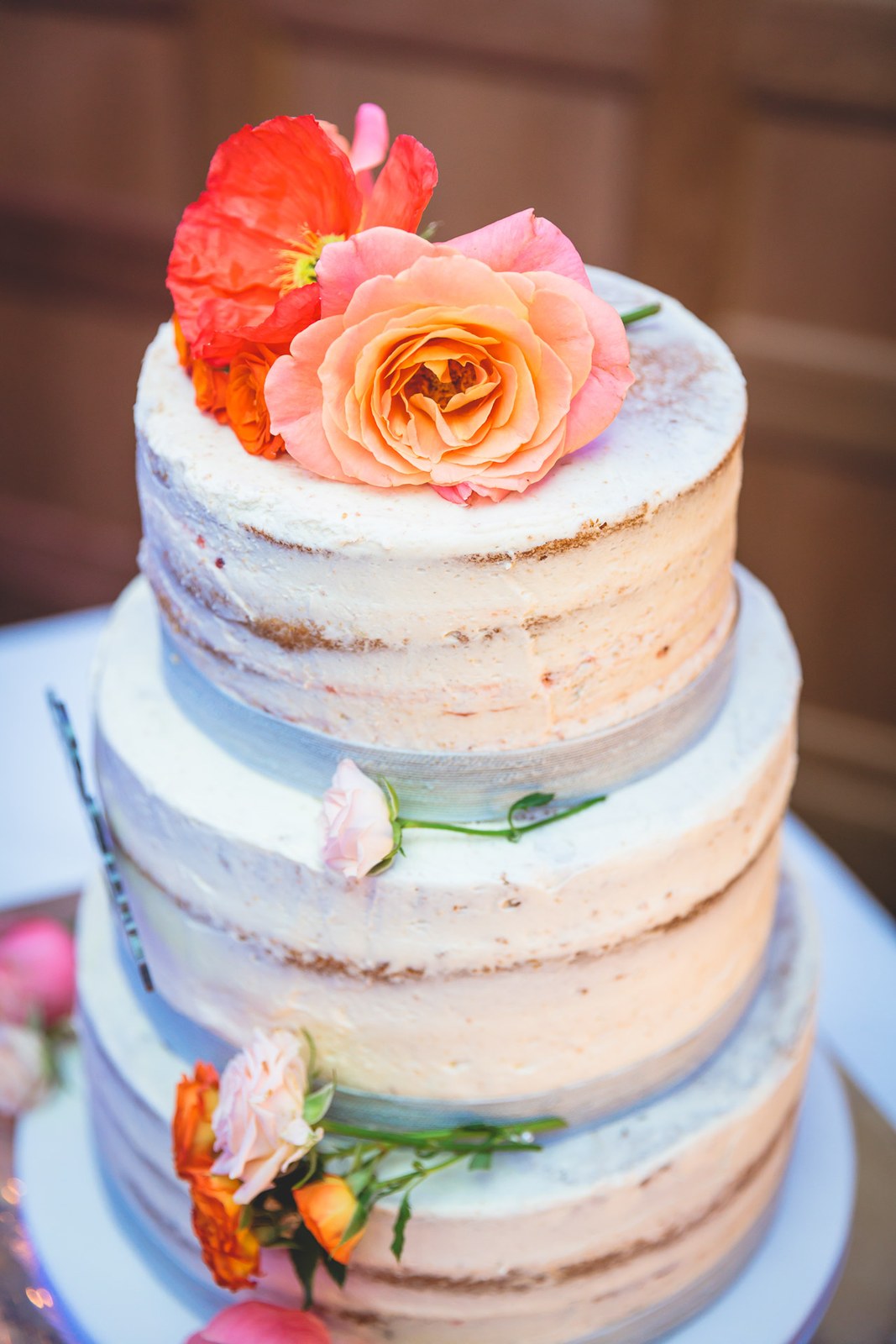 Close-up of the semi-naked wedding cake topped with a coral rose