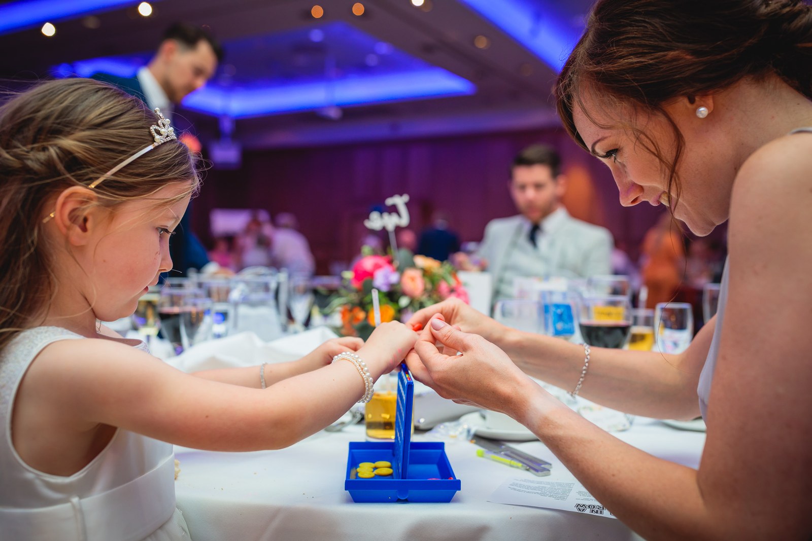 A flower girl and a guest playing a table game during the reception