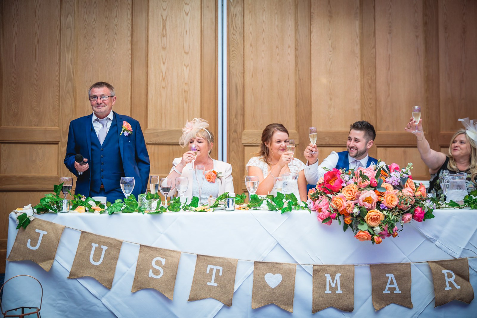 The wedding party toasting at the top table beneath a Just Married banner