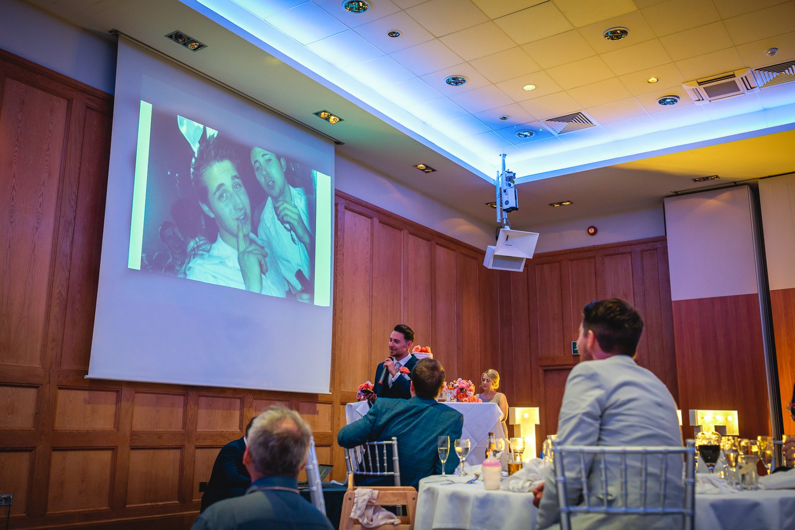 A guest giving a speech as a slideshow photo is projected on the screen