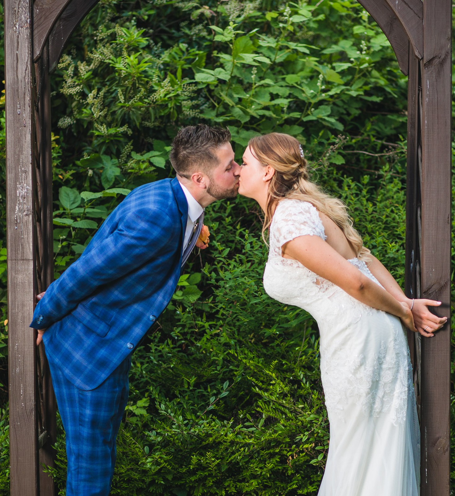 The couple kissing beneath the wooden garden arbour