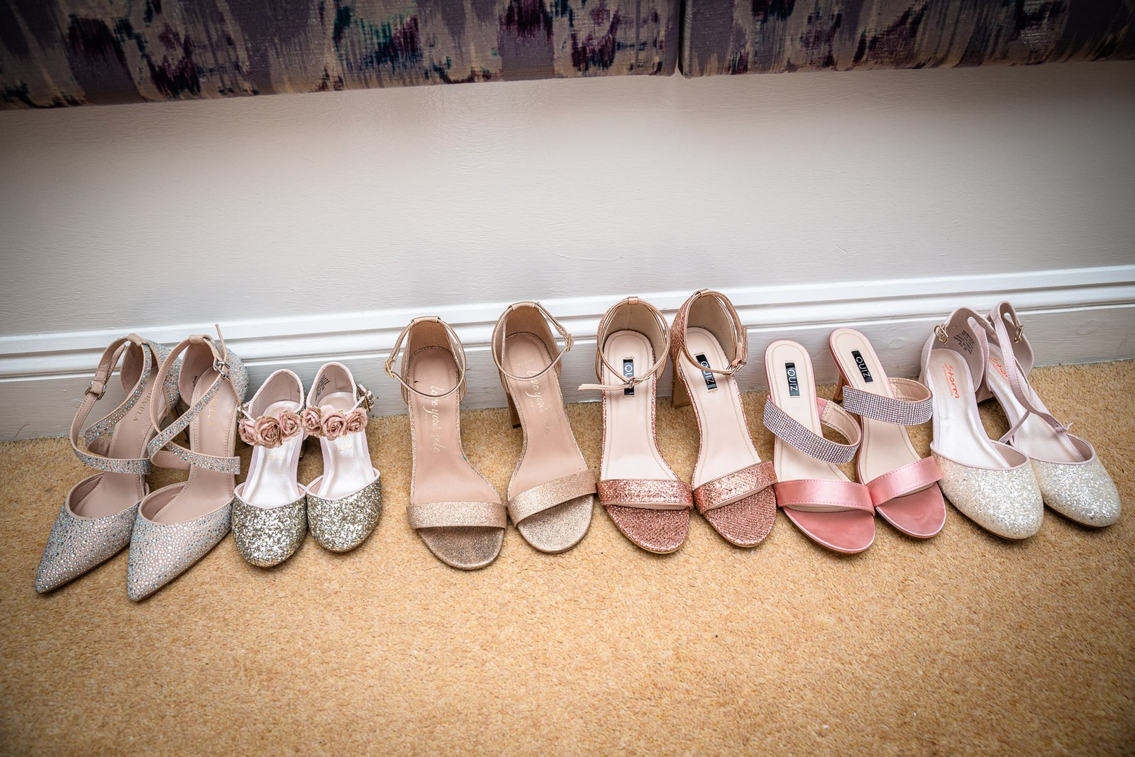 A row of the bride's and bridesmaids' sparkly heels lined up on the floor