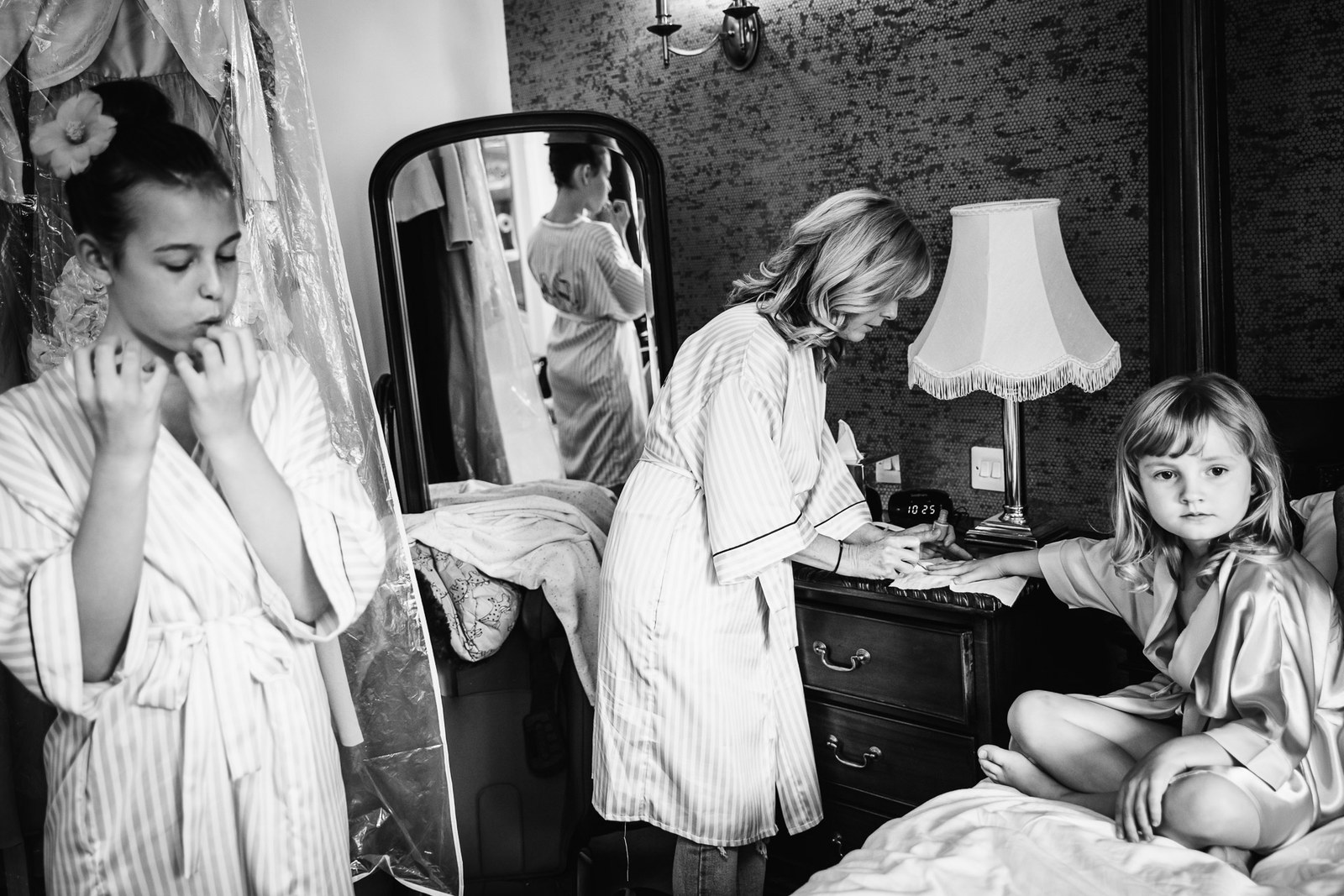 Black and white of bridesmaids and a flower girl getting ready in the bedroom