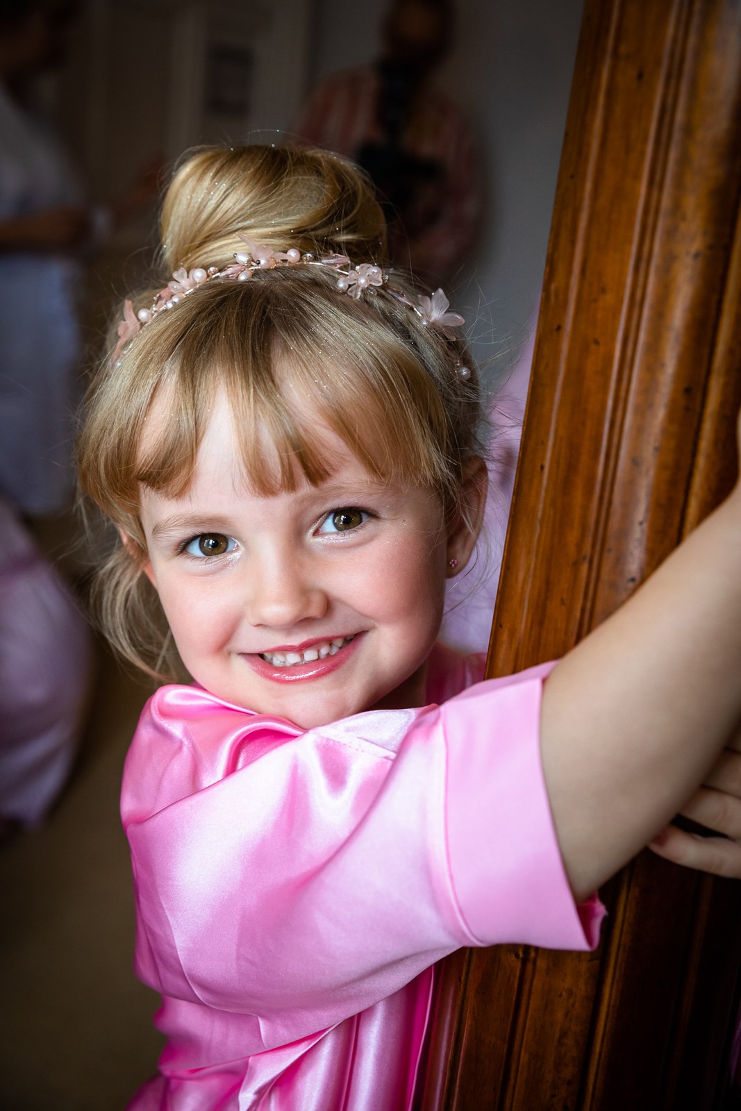 Portrait of a smiling flower girl in a pink robe and floral hairband