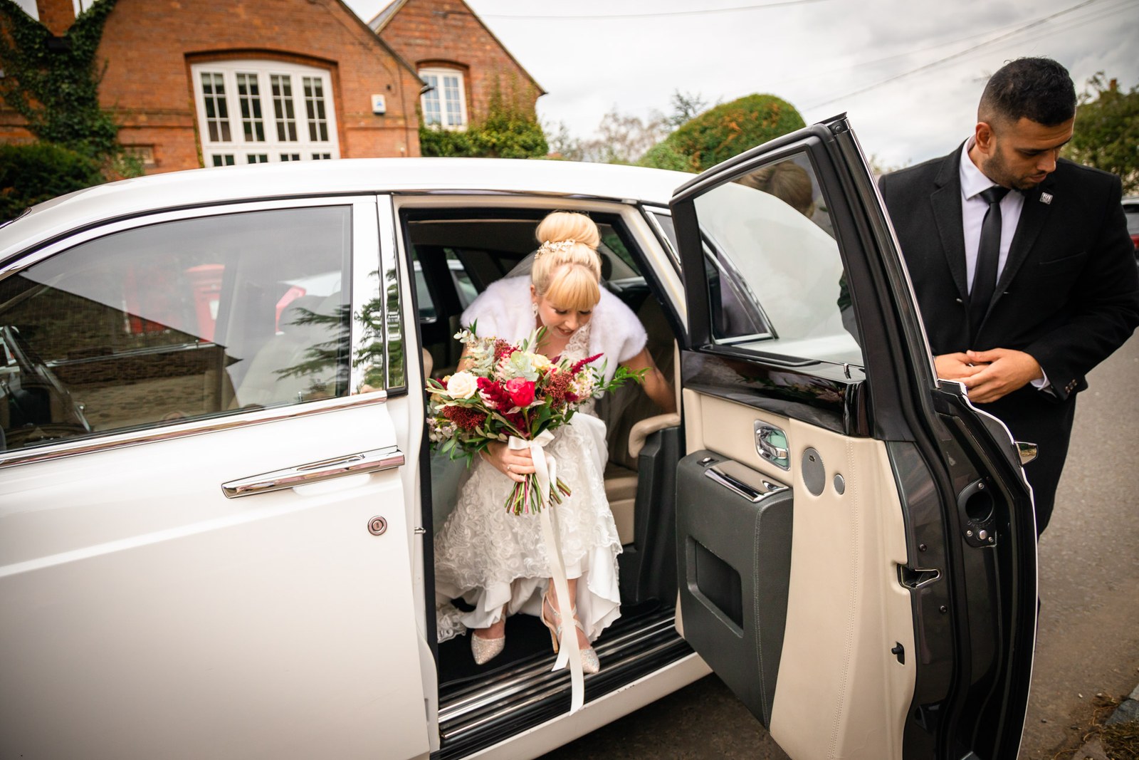 Bride stepping from the white Rolls-Royce as the chauffeur holds the door